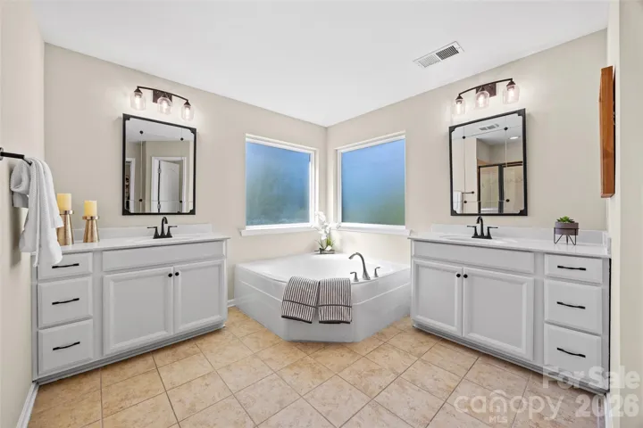 Primary en-suite bathroom w/ double vanities, large garden tub and stall shower