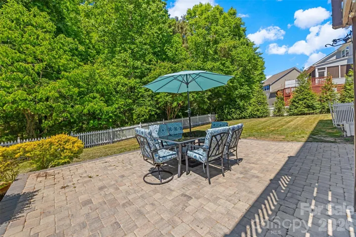 Paver patio overlooks fully fenced flat backyard and mature trees