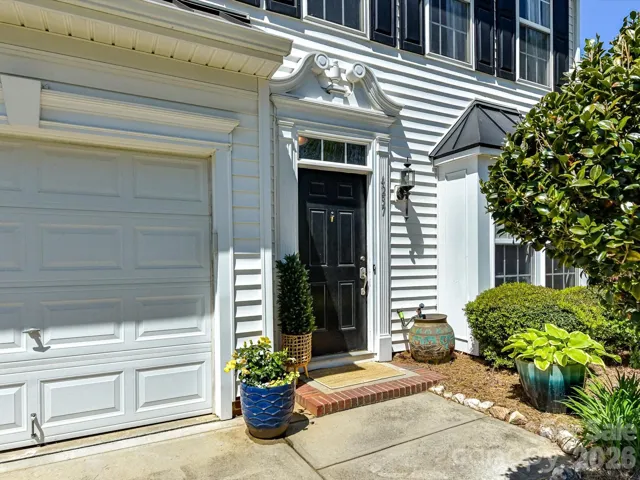 Charming entry with classic black front door, decorative trim, and inviting landscaping creates a warm and welcoming first impression.
