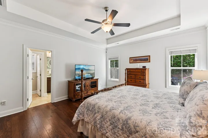 Primary bedroom featurs tray ceiling and fan