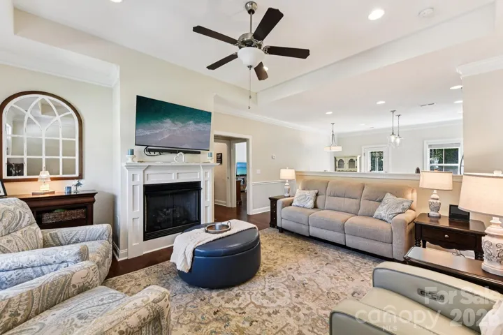 Living room has tray ceiling, can lights, and gas log fireplace