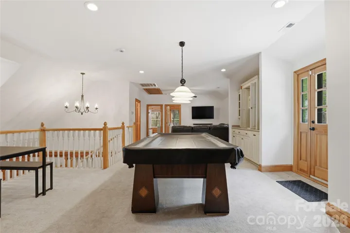 Large living / flex / game room, shows door that leads to upper outside deck over looking the pool.