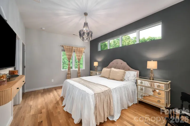 Spacious primary suite with bold accent wall, clerestory windows, and serene treetop views.