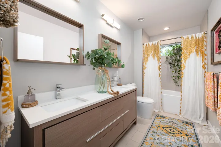 Full bath with double vanity and tiled tub/shower.