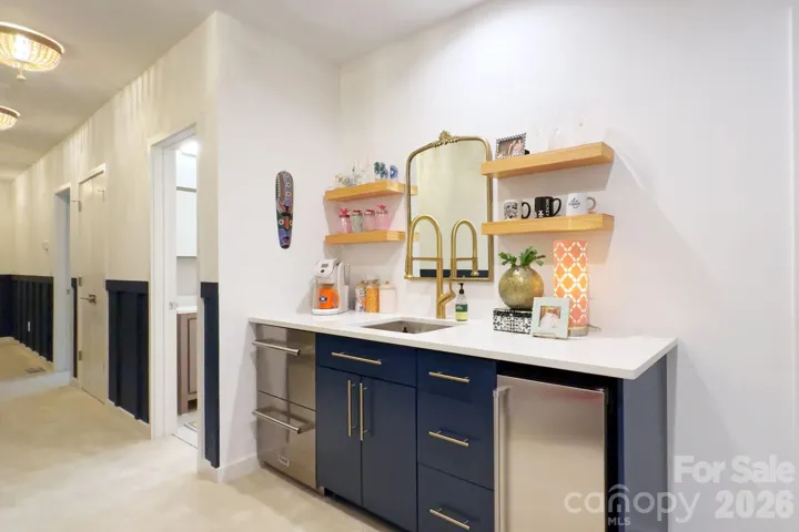 Custom stylish wetbar area with beverage fridge and floating shelves.