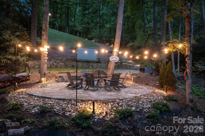 Flagstone patio with a central fire pit, and string lights, create an inviting space for gatherings.