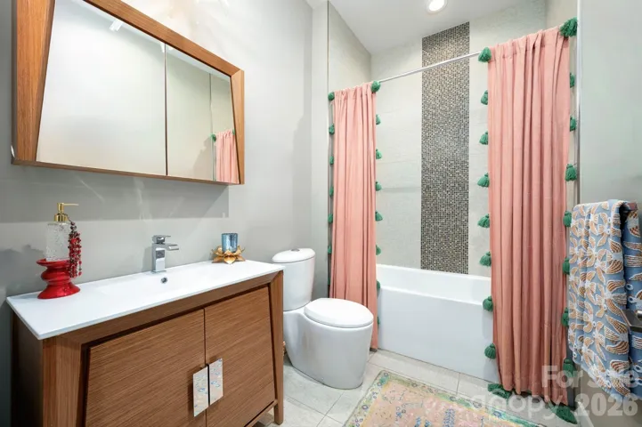 Stylish full bath with modern vanity and tiled tub/shower.