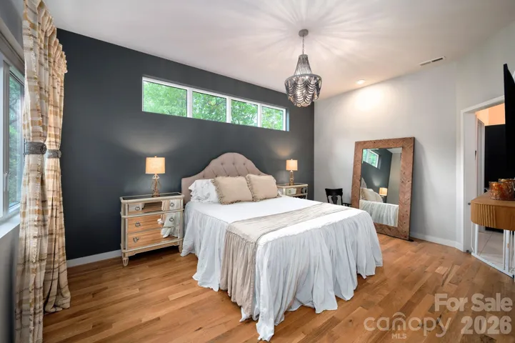 Spacious primary suite with bold accent wall and clerestory windows with serene treetop views.