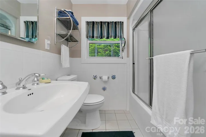 The primary suite bathroom is white, light and bright.