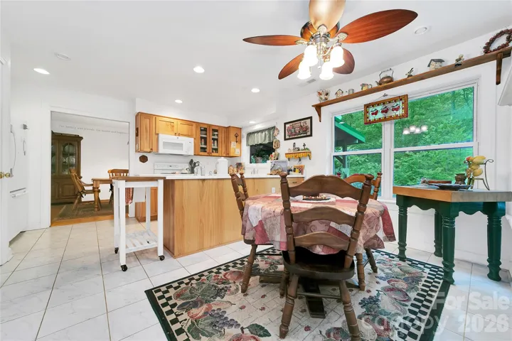 The breakfast nook is adjacent to the kitchen and looks out to the super green foliage in the back. Refrigerator is visible on the far left.