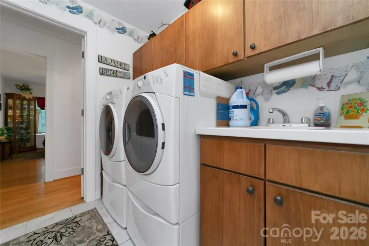 Laundry room is full of storage cabinets and has a work sink and counter. It is a walkthrough room from the hallway to the rear sunroom.
