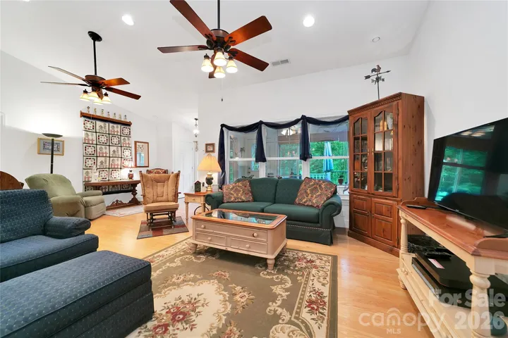 Looking out of the living room windows through the sunroom to the front deck to the green of the front yard.