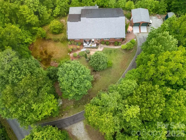 This view shows the short driveway with no major curves, straight to the garage doors. You can also see the front deck, the front sitting garden with it's bridge to the side yard, possible garden area. Left side of the house is fenced and accessible from the screen porch in back.