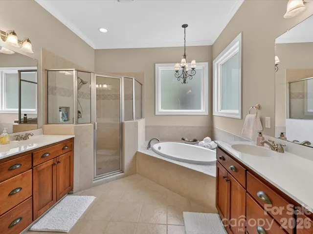 Spa-like primary bath featuring dual vanities, a gargen tub, separate glass-enclosed shower, and elegant finishes throughout.