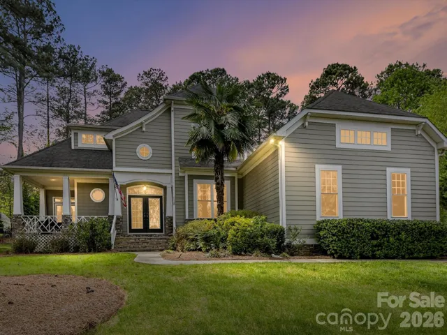 Charming Southern-style home with inviting front porch, lush landscaping, and a beautifully maintained exterior set beneath mature trees for added privacy and curb appeal.