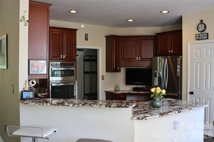 Kitchen with custom cabinets, granite counter tops, and computer niche, coffee bar or television area.