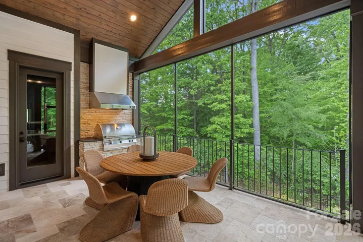 Spacious screened-in porch with built-in gas grill, access to half bath and view of pool.