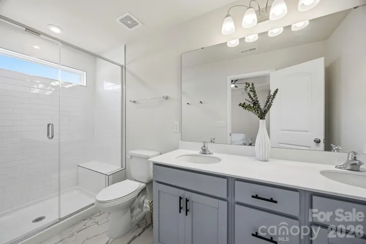 Primary bath with dual sinks and tiled shower with bench seat