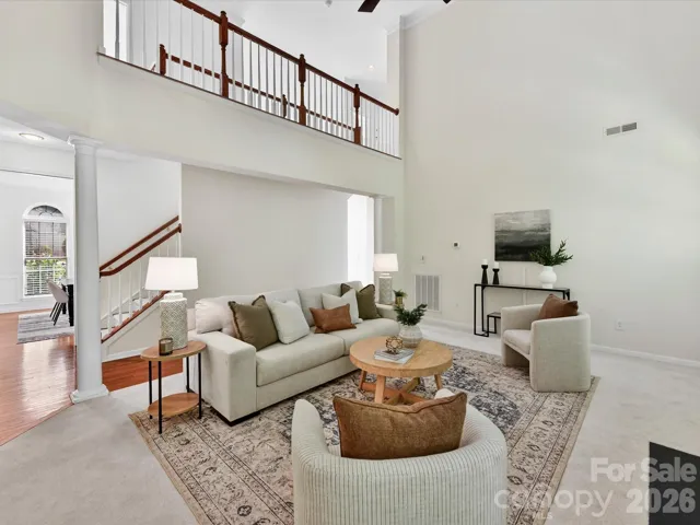 Stunning two-story great room with soaring ceilings, expansive windows, and cozy fireplace seamlessly opens to the kitchen, creating a bright and inviting space ideal for everyday living and entertaining.