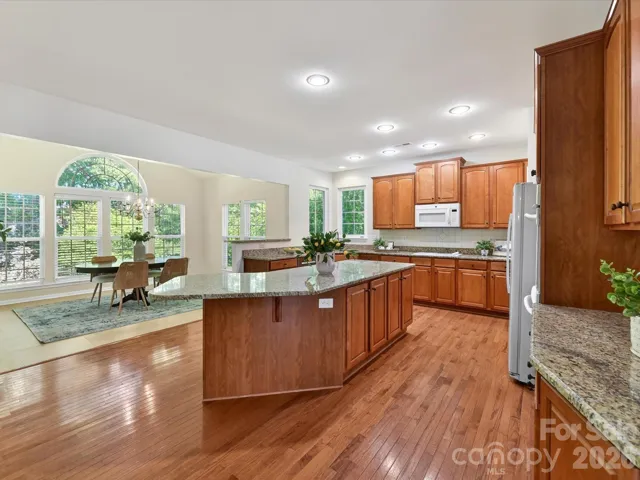 Spacious chef’s kitchen featuring granite countertops, oversized island with seating, abundant cabinetry, and seamless flow to the breakfast area and main living spaces.