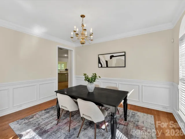 Elegant formal dining room with crown molding, wainscoting, arched windows, and a classic chandelier, filled with natural light and open to the foyer.