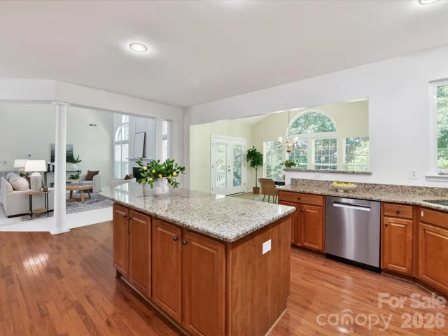Spacious chef’s kitchen featuring granite countertops, oversized island with seating, abundant cabinetry, and seamless flow to the breakfast area and main living spaces.