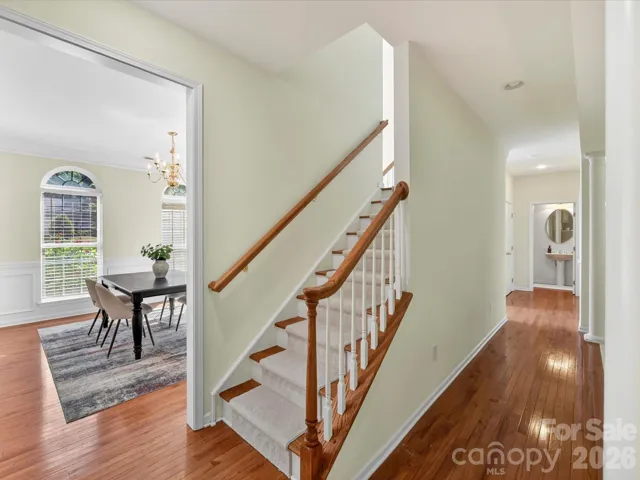 Elegant staircase with wood handrails and classic white balusters leads to the upper level, adding architectural charm to the home’s open layout.