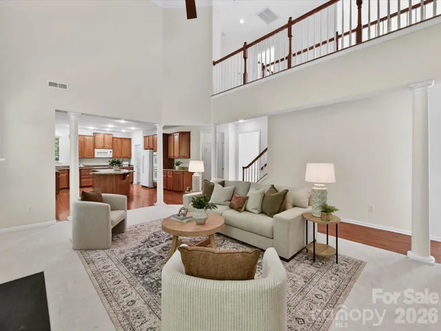 Stunning two-story great room with soaring ceilings, expansive windows, and cozy fireplace seamlessly opens to the kitchen, creating a bright and inviting space ideal for everyday living and entertaining.