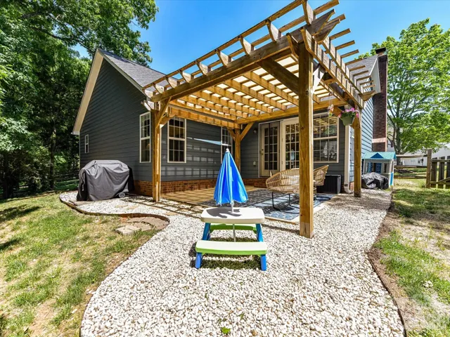 Beautiful outdoor patio with a wood pergola offers a shaded retreat perfect for relaxing or entertaining while overlooking the private, tree-lined backyard.