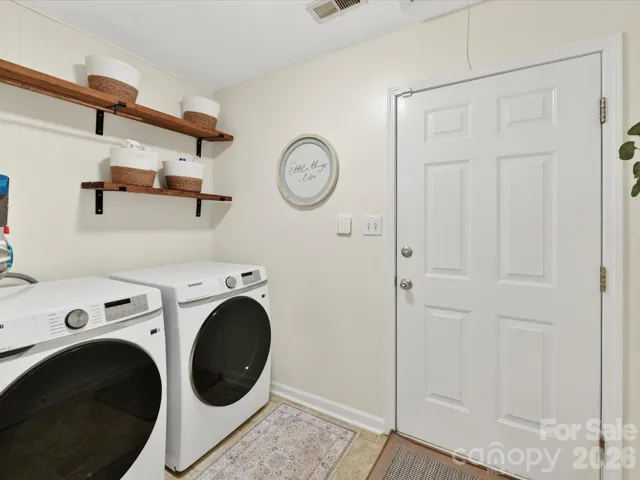 Convenient laundry room features modern washer and dryer, built-in shelving for storage, and easy access for everyday functionality.
