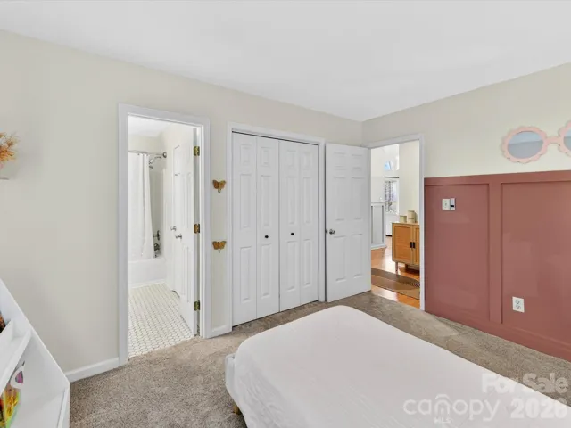 Charming secondary bedroom features soft natural light, plush carpeting, and convenient access to a nearby full bath—perfect for guests or family.