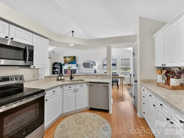 Bright, updated kitchen features granite countertops, white cabinetry, stainless steel appliances, and an open layout overlooking the great room.