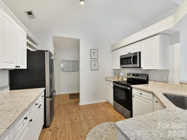 Bright, updated kitchen features granite countertops, white cabinetry, stainless steel appliances, and an open layout overlooking the great room.
