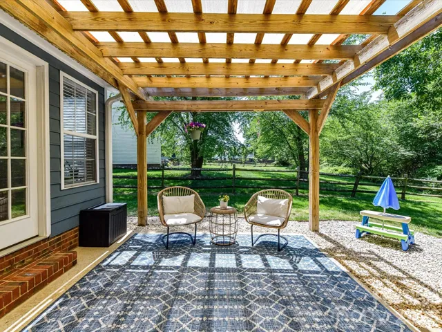 Beautiful outdoor patio with a wood pergola offers a shaded retreat perfect for relaxing or entertaining while overlooking the private, tree-lined backyard.