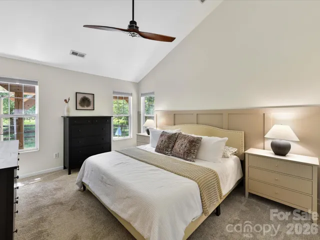Generously sized primary suite features vaulted ceilings, plush carpeting, abundant natural light, and a private en-suite bath for added comfort.