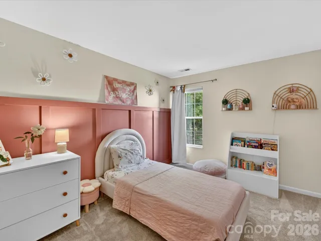 Charming secondary bedroom features soft natural light, plush carpeting, and convenient access to a nearby full bath—perfect for guests or family.