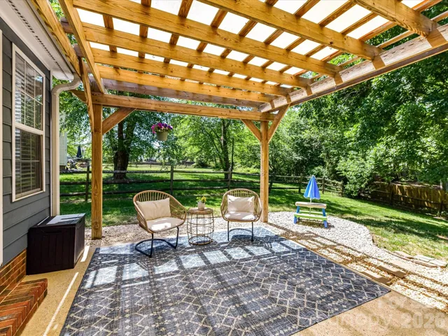 Beautiful outdoor patio with a wood pergola offers a shaded retreat perfect for relaxing or entertaining while overlooking the private, tree-lined backyard.