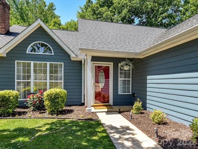Welcoming front entry with charming curb appeal, highlighted by a vibrant door, manicured landscaping, and inviting walkway.