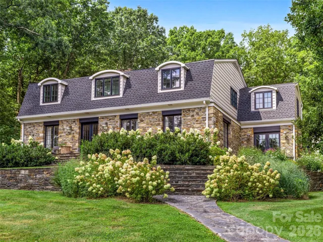 1912 stone exterior with stone paths and professionally designed gardens, surrounding the property.