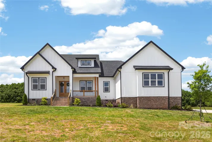 Modern farmhouse design with clean white board and batten siding, black accents, and rich wood details that make this home stand out. Sitting on a spacious lot, the exterior combines custom style with timeless curb appeal and a welcoming front porch entrance