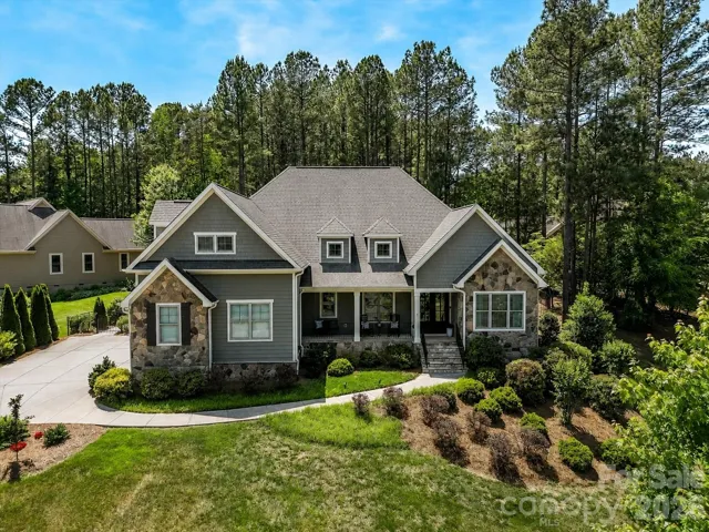 Beautiful craftsman-style home with stunning stone accents, manicured landscaping, and a welcoming front porch nestled on a spacious, tree-lined lot.