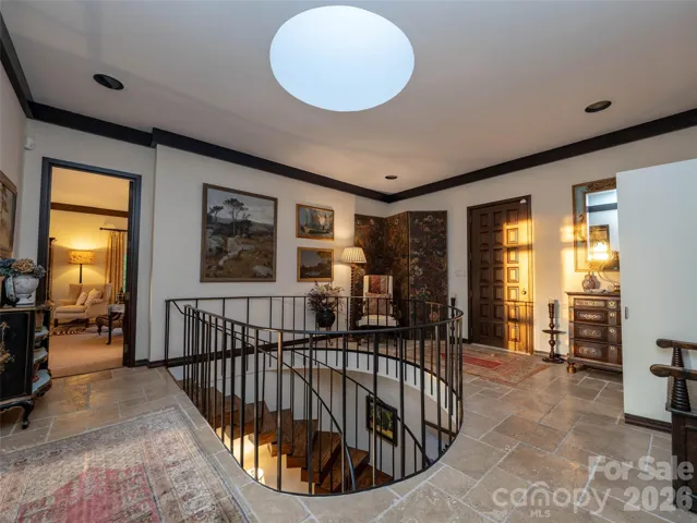 A 1970s front door embracing a piece of architectural history opens to early morning or late afternoon light from the original skylight that highlights circular staircase