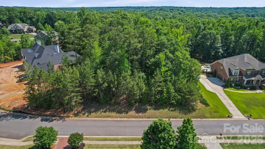 Property is the wooded area between the house under construction and the house with the pool.