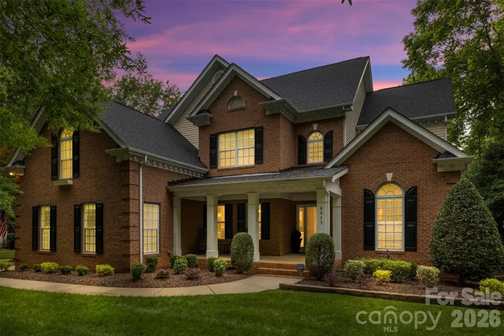 Brick-front craftsmanship on a premium corner lot with covered front porch and mature landscaping.