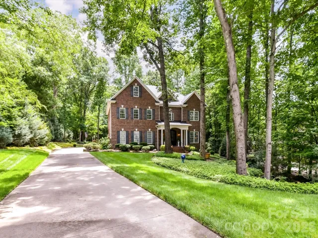 Stunning brick traditional nestled on a private wooded lot featuring timeless curb appeal, manicured landscaping, and a welcoming covered front porch.