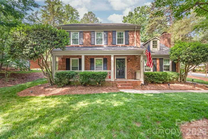 Beautiful front exterior view of the home with mature trees and a manicured lawn.
