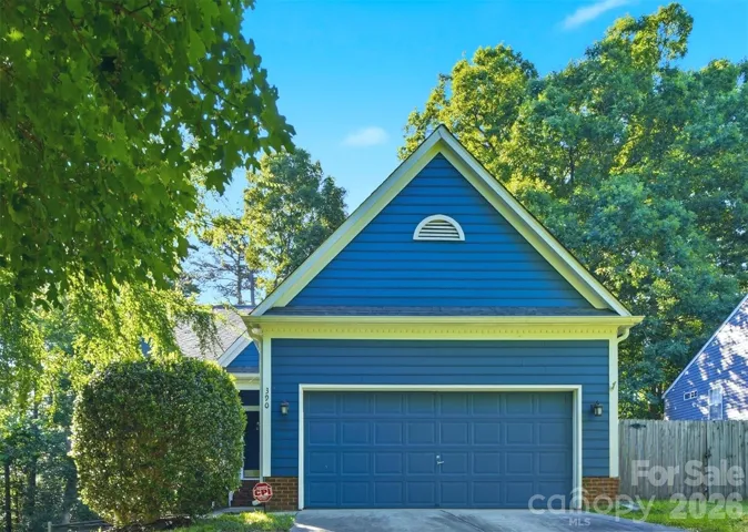 Front of home showing all new paint, large 2-car garage, mature foliage and fenced in back yard.