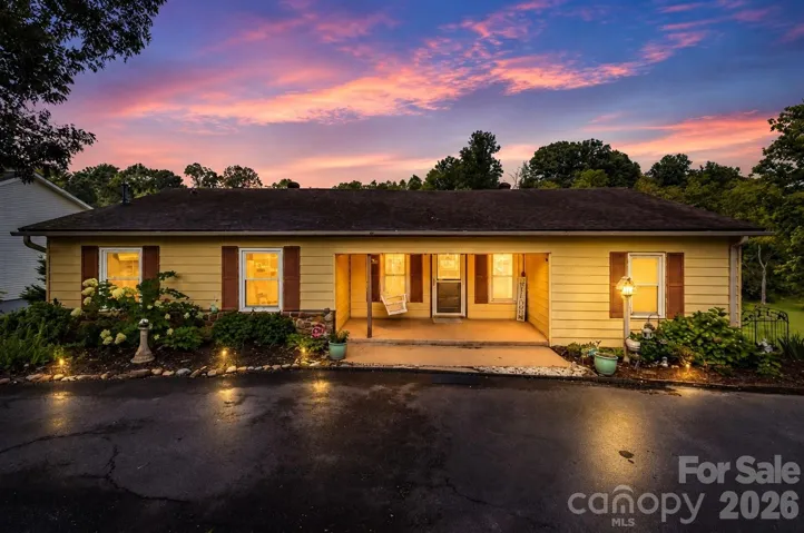 Virtual twilight, inviting curb appeal with mature landscaping, a covered front porch and convenient crescent-shaped driveway with two access points.