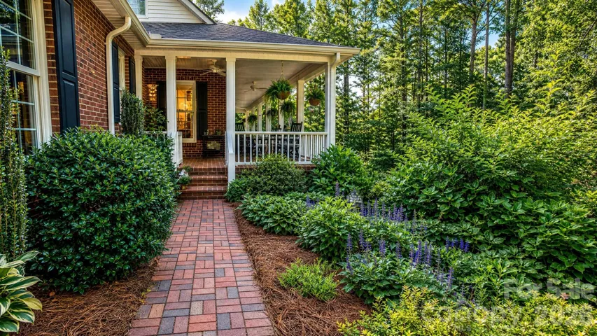 Paver sidewalk leads guests to side porch entrance, past gorgeous garden.