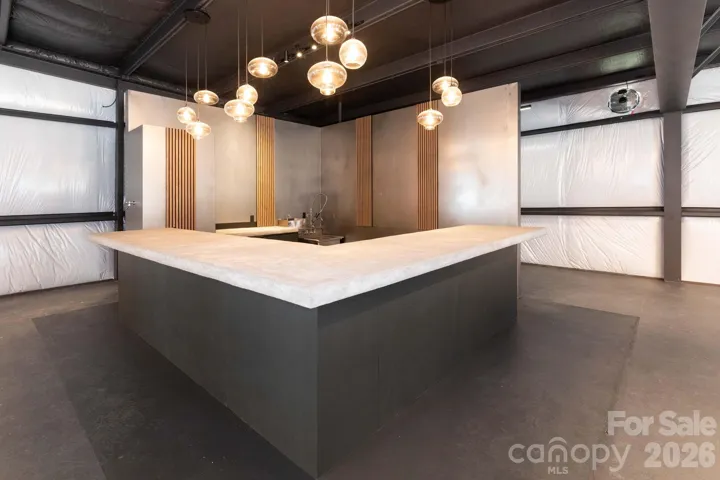 Custom-built commercial bar featuring a poured concrete countertop, modern pendant lighting, and an inviting layout designed for customer interaction.